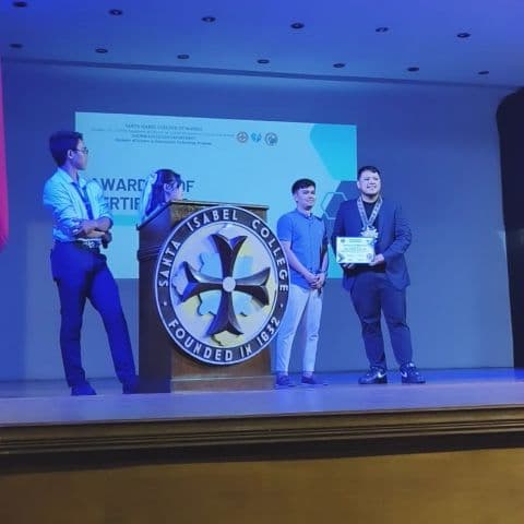 Award ceremony at Santa Isabel College with JC and recipients on stage holding certificates