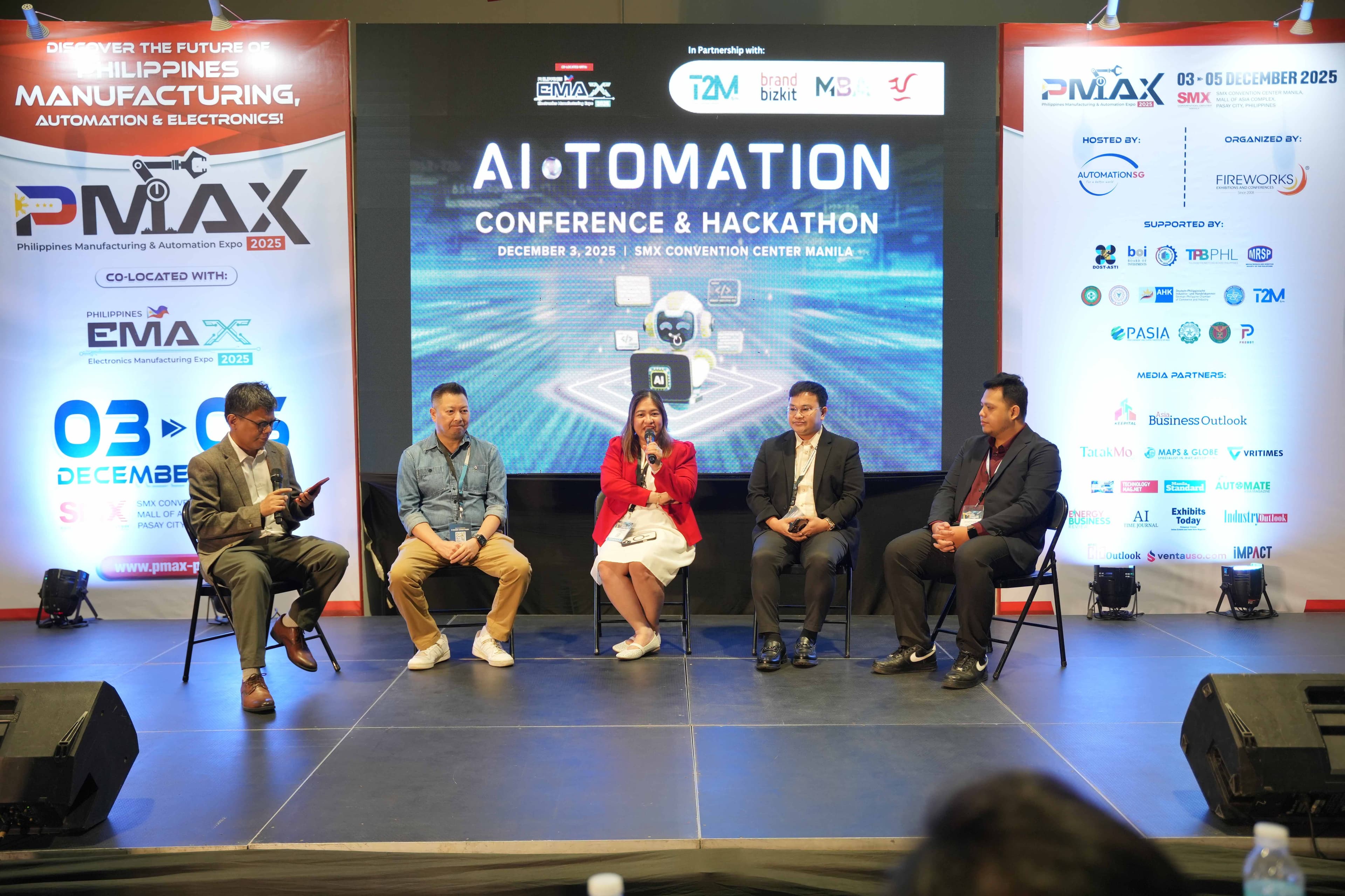 Full stage view of AI-TOMATION Conference fireside chat with five panelists and conference backdrop