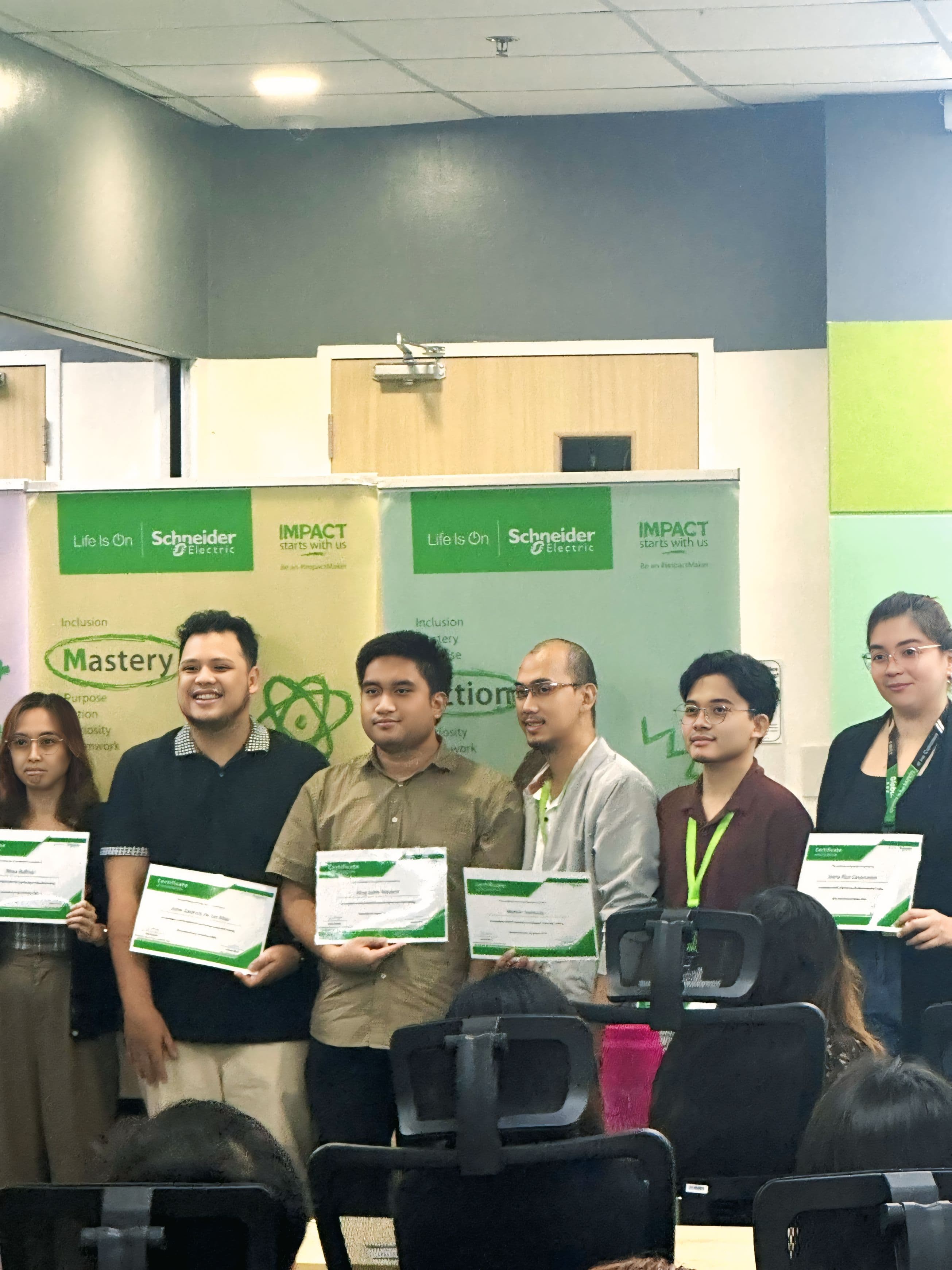 JC and colleagues holding Lean Six Sigma Green Belt certificates at Schneider Electric recognition event