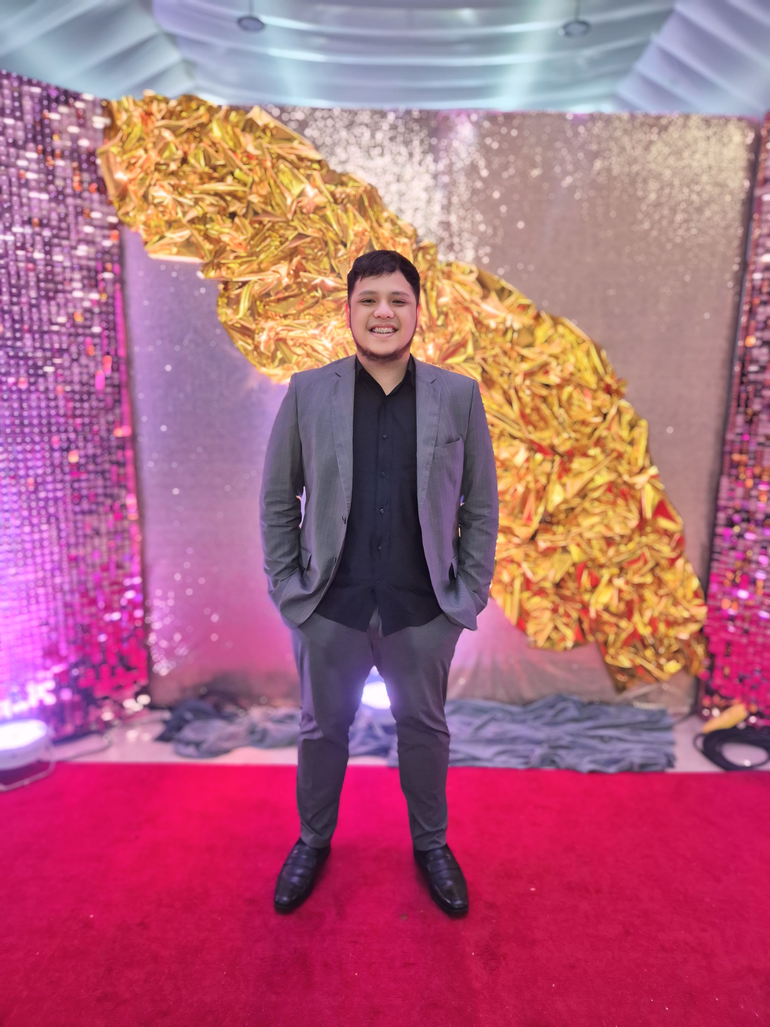 JC on the red carpet at an industry awards gala with dramatic gold Philippines map backdrop