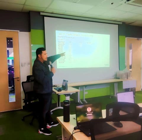 JC teaching a Tableau bootcamp session at Schneider Electric, gesturing at projection screen